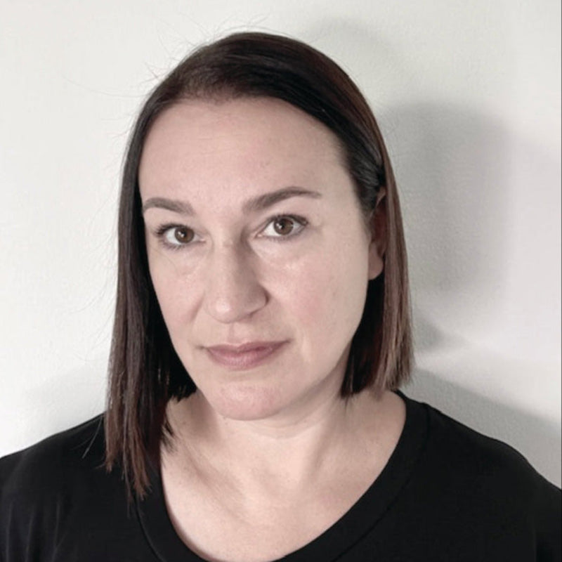 Woman with shoulder-length brown hair wearing a black shirt against a white background